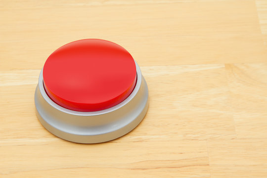 A Blank Red Push Button On A Wooden Desk