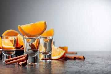 Glasses of tequila with orange and cinnamon sticks.