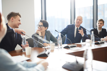 Diverse group of business people talking and gesturing while participating in active discussion at conference table, copy space