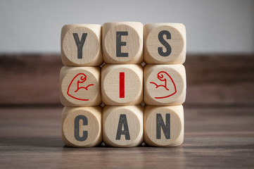 Cubes and dice with slogan Yes I Can on wooden background 