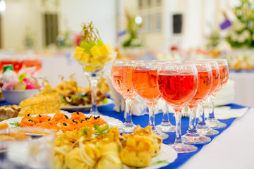 Pink wine in glasses. Festively laid tables at the Banquet. Various delicacies, snacks and drinks. Catering.