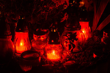 Candles in elegant red glass lanterns on a tombstone - all souls night decoration in the dark - european christian cemetery