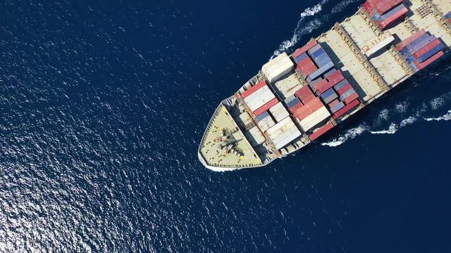 Aerial video of large cargo container ship cruising the deep blue Mediterranean sea