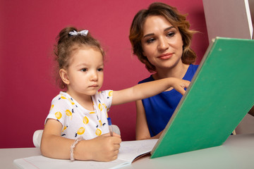 Mom with little baby girl together at home sitting at the table