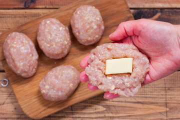 Step-by-step preparation of homemade turkey cutlets with cheese filling, step 2 - putting the cheese fillings into cutlets, top view, selective focus