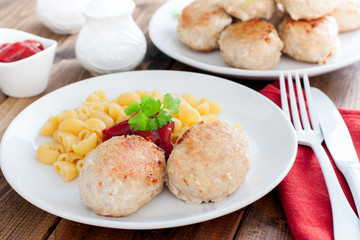 Homemade turkey cutlets with cheese filling on a white plate on a wooden table, horizontal