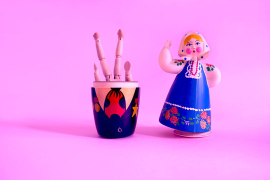 Pink background with wooden doll upside down in a wooden doll with a stuffed doll.....