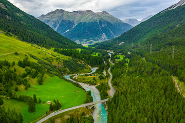 Inn River flowing in the forest in Switzerland. Aerial view from drone on a blue river in the mountains