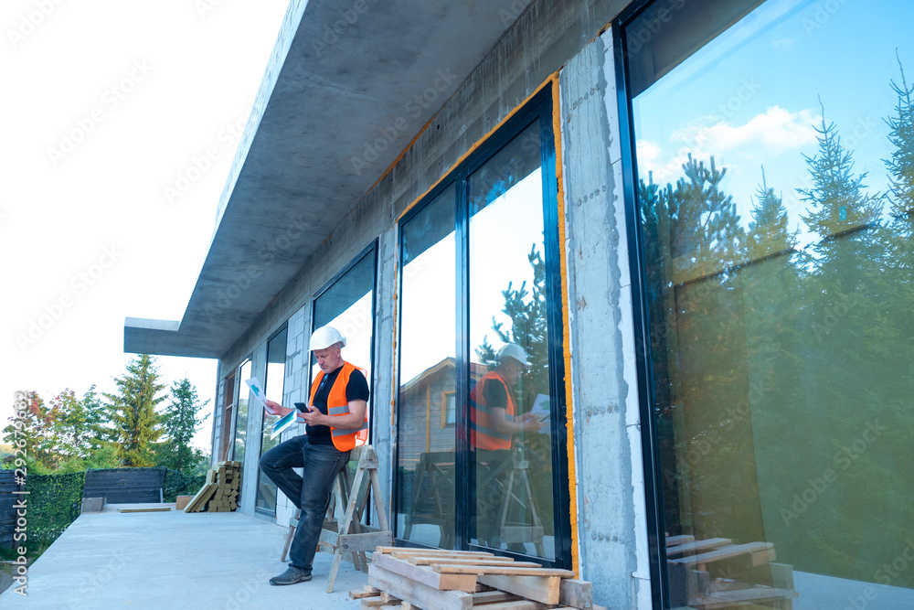 Aufkleber the builder stands next to the building under construction. panoramic windows of the house. the stud