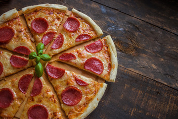 sliced pepperoni pizza on wooden background copy space