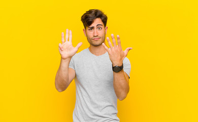  smiling and looking friendly, showing number nine or ninth with hand forward, counting down