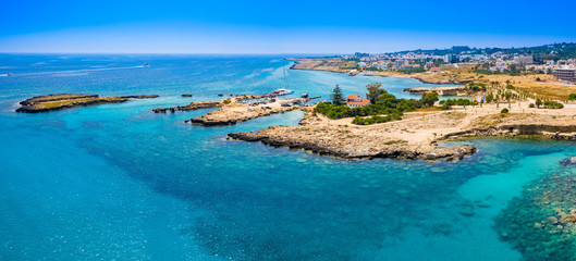Panorama of Cyprus on a Sunny day. The mediterranean coast. The Port Of Pernera. There's a yacht in the Harbor. The house with a brown roof is located on a picturesque Cape. Rest, vacation, relaxation