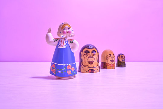 Pink background with a painted doll and a face painted on a barrel.