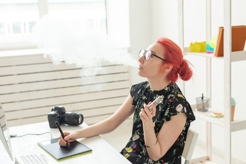 Creative, graphic designer, people concept - young creative woman smoking a vape while working in a...