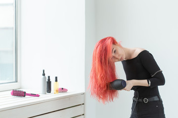 Hairdresser, beauty salon and people concept - young woman hair stylist with hair dryer on white background