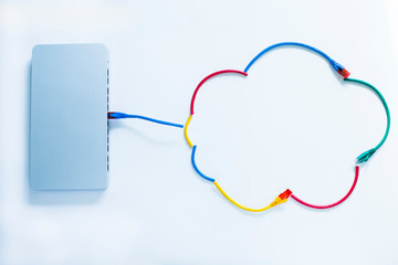 Cloud services concept. Bright cloud logo made from cables connected to the cloud switch port and endpoints. Public clouds concept for corporate enviroment. Closeup.