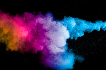 Plakat Freeze motion of colored powder explosions isolated on black background.Color dust particle splatter on background.