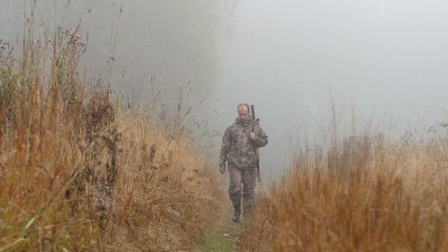 The hunter is on the road. Early morning, fog. Autumn, yellow grass along the road.