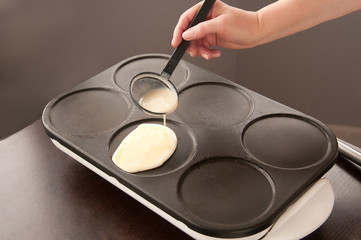 Woman cooks pancakes, pours batter on a hot stove