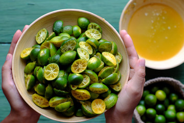 Top view people hand hold kumquat peel in green