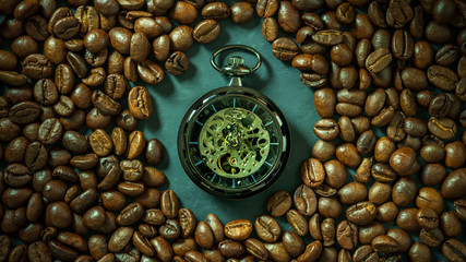 Coffee bean around pocket watch on table in morning. Concept of coffee time.
