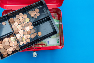 a lot of euro banknotes lie spread out in a red cash box