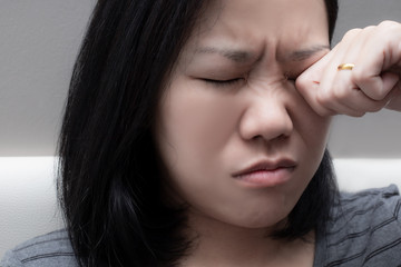 Asian woman rubbing her eye. because of  eye's problem, dust allergy, dry eye, watery, itching or contact lenses problem