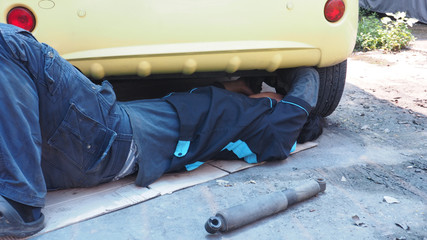 Shock absorber replacement by Asian mechanic he is working under the car