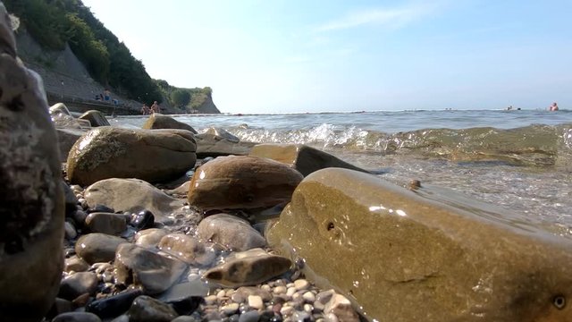 Slow motion low angle sea waves hitting rocky shore