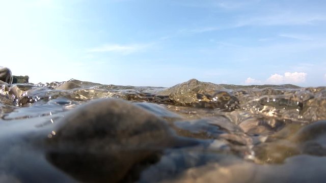 Slow motion sea waves hitting and flooding rocky shore
