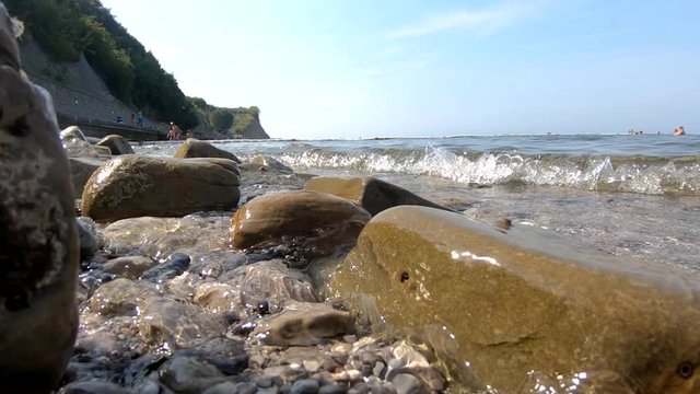 Slow motion sea waves hitting and flooding rocky shore
