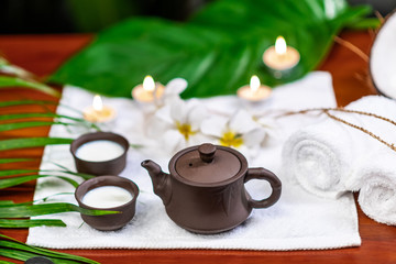 Tea ceremony accessories located on a white terry towel with candles and white flowers