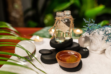 Two jars of aromatic oils standing on stones for a therapy stone and located on a terry towel next to which are transparent spheres, a twisted white terry towel