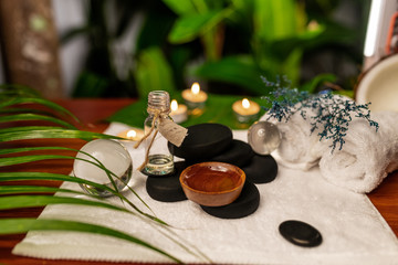 Two jars of aromatic oils standing on stones for a therapy stone and located on a terry towel next to which are transparent spheres, a twisted terry towel of white color and...