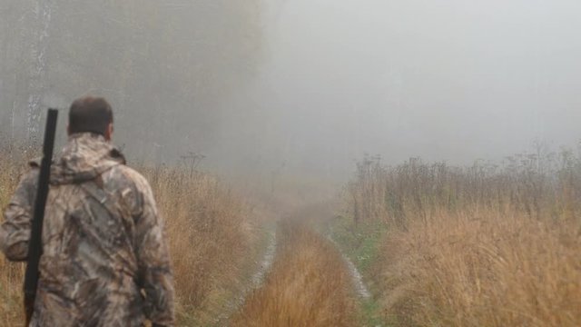 The hunter is on the road. Early morning, fog. Autumn, yellow grass along the road.