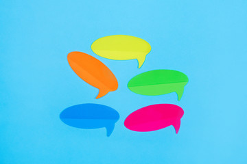 Sticker in the form of a cloud for the message of orange, yellow, pink, blue and green in the center on a blue background. Close-up. Free space for notes. Goods for school.