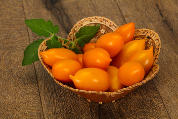 Yellow tomato heap in the wooden bowl