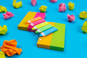 Sets of colored stickers in the form of stripes on top of which are stickers in the form of pencils, next to which are crumpled stickers of various colors. Close-up. Accessories for the office.