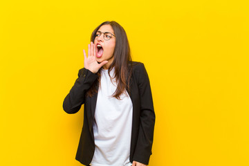 young  pretty woman yelling loudly and angrily to copy space on the side, with hand next to mouth...