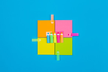 Four small sets of yellow, orange, pink, green stickers folded in a square in the center of which are stickers pencils on a blue background on each sticker is sticked in the form of a pencil.