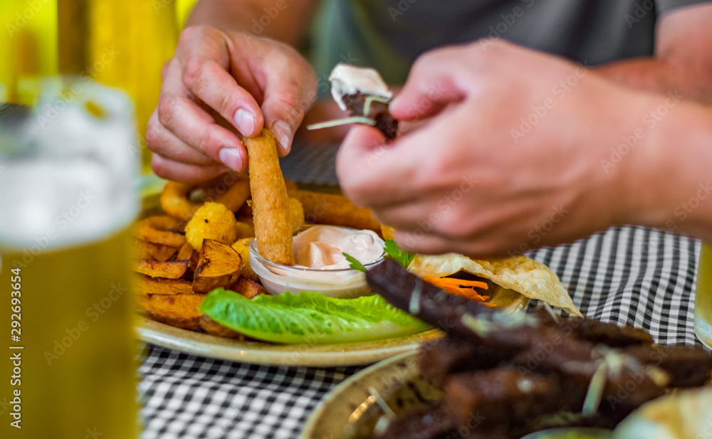 Wall mural man hand with plate with snacks on table background on bar or pub