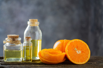 Three bottles with essential oil, orange slice, peel on wooden table.aromatherapy oil natural organic cosmetic.