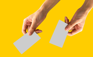 Woman hand hold name card or credit card in right and left hand with yellow pastel background. with clipping path