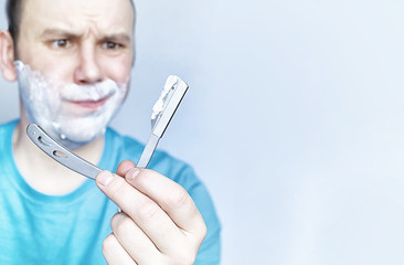 A man shaves in front a mirror. Shaving foam. Disposable razor.