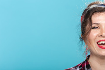 Close-up portrait of a charming young pin-up woman in a plaid shirt against a blue background with...