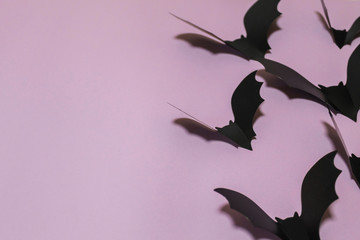 halloween, decoration and scary concept - black bats flying over lilac background