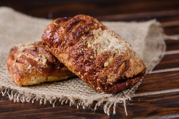Puffs with cherry jam on burlap on a wooden background. Rustic style