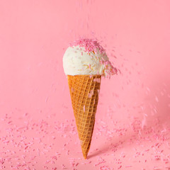 summer creative concept with ice cream cone and dynamic strewing pink sprinkles on background, festive background for Valentines day, birthday, holiday and party time