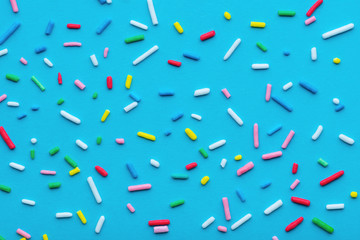Fototapeta na wymiar colorful sprinkles over blue background, festive decoration for Valentines day, birthday, holiday and party time