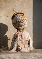 Verwitterte Puppe auf einem Grab